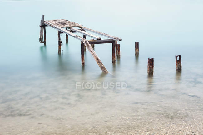 Abandoned broken poles of pier in crystal water in Halkidiki — Stock Photo