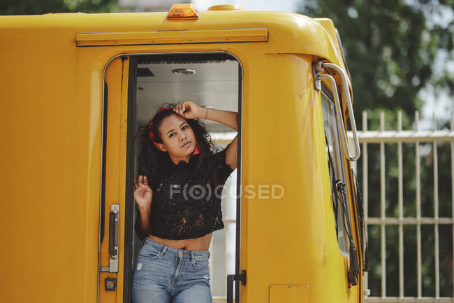Young cheerful beautiful hispanic woman standing on yellow train in drivers cabin in Berlin looking at camera — Stock Photo
