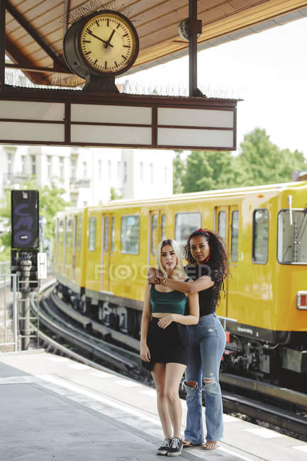 Belle giovani donne in piedi sulla piattaforma ferroviaria il giorno d'estate a Berlino guardando la fotocamera — Foto stock
