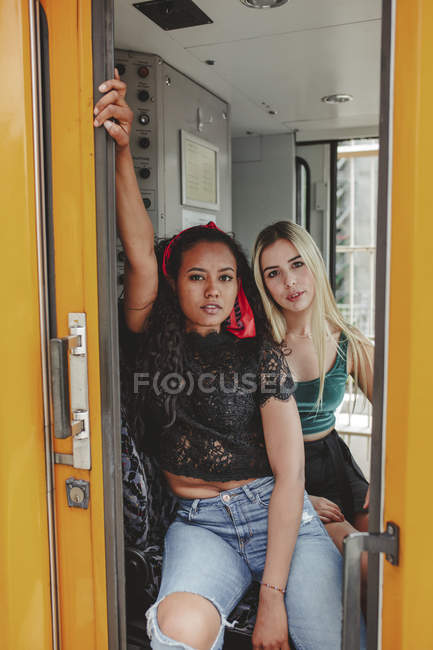Hermosas mujeres jóvenes sentadas en cabina de maquinistas en Berlín mirando a la cámara - foto de stock