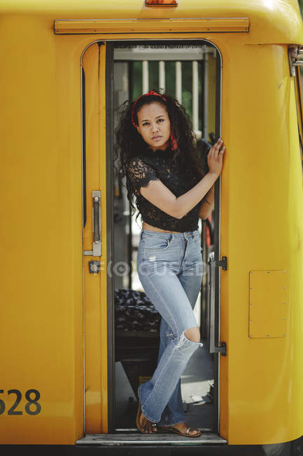 Jeune jolie hispanique joyeuse se tenant debout à bord d'un train jaune dans la cabine des conducteurs à Berlin regardant la caméra — Photo de stock