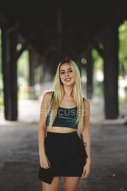 Beautiful blonde model smiling and looking at camera in Berlin on blurred background looking at camera — Stock Photo