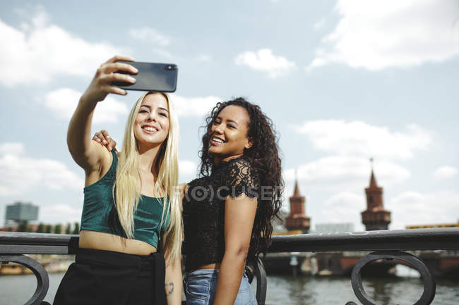 Young beautiful cheerful women taking selfie with phone in Berlin on summer day — Stock Photo