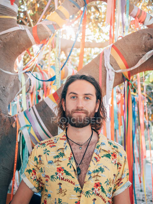 Pensieroso bello barbuto hipster uomo in piedi sotto albero decorato guardando in macchina fotografica — Foto stock