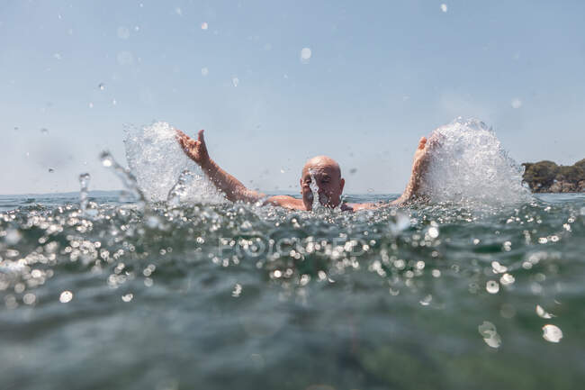 Bald mustache elderly man enjoying and splashing water in bright sunny day in Greece Halkidiki — Stock Photo
