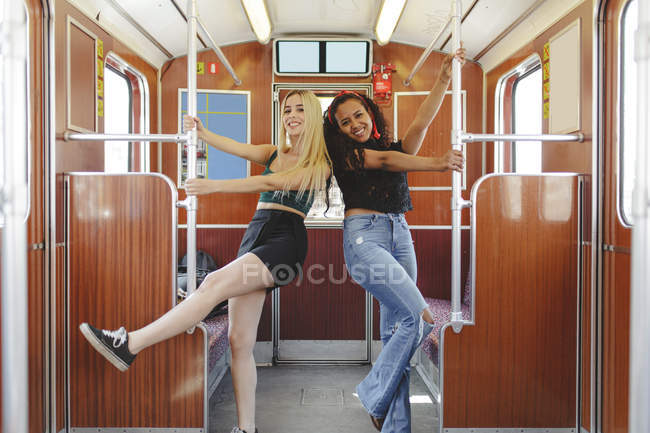 Веселые многорасовые женщины в вагоне поезда в Берлине смотрят в камеру — стоковое фото