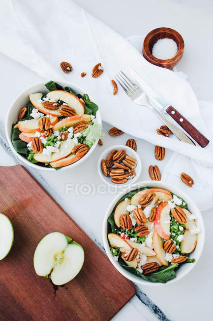 Bols servis avec des pommes coupées et salade de pacanes sur la table — Photo de stock