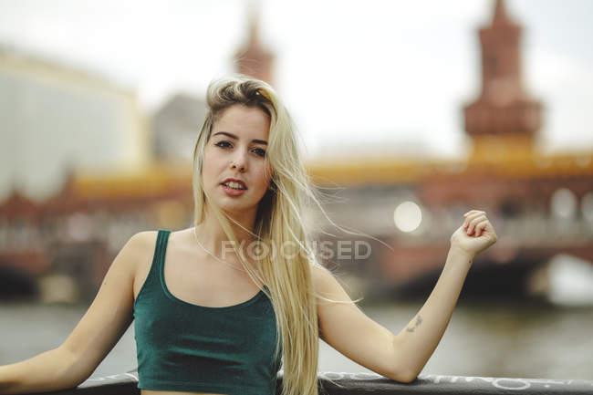 Schöne blonde Model lehnt an Geländer an Sommertag in Berlin auf verschwommenem Hintergrund Blick in die Kamera — Stockfoto