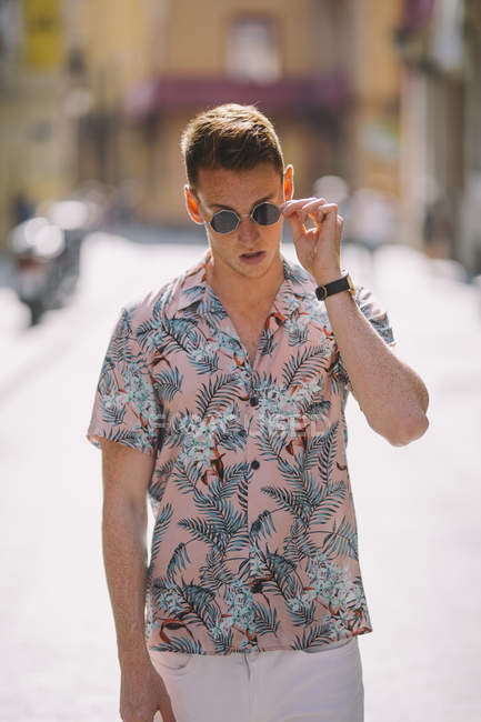 Bello maschio in camicia hawaiana in piedi sulla strada con occhiali da sole — Foto stock