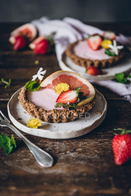 De porções acima de deliciosos bolos de morango e cítricos servidos em mesa de madeira decorada — Fotografia de Stock
