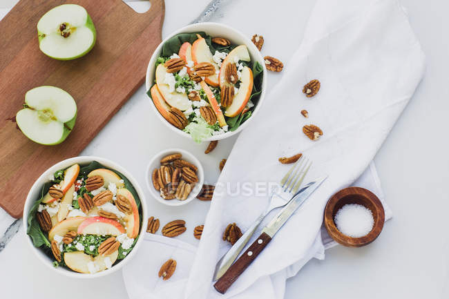 Served bowls with cut apples and pecans salad on table — Stock Photo