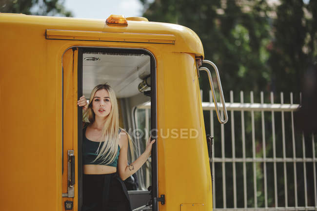 Молодая жизнерадостная красавица-блондинка стоит в желтом поезде в кабине машиниста в Берлине, глядя в камеру — стоковое фото