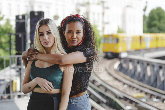 Belle giovani donne in piedi sulla piattaforma ferroviaria il giorno d'estate a Berlino guardando la fotocamera — Foto stock