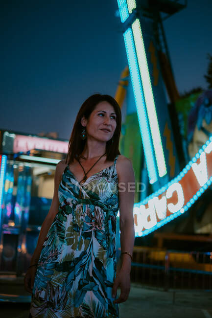 Woman wearing summer dress and spending time in amusement park on blurred background — Stock Photo