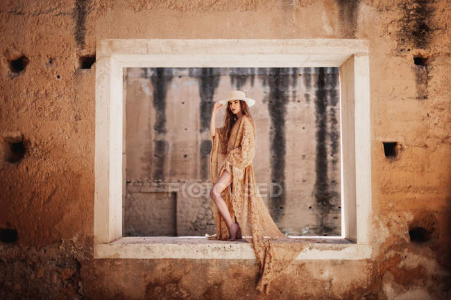 Elegant woman in long dress on window — Stock Photo
