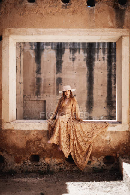 Femme élégante en robe longue sur la fenêtre — Photo de stock