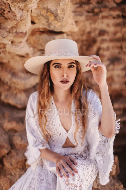Gorgeous woman sitting by ruined wall — Stock Photo