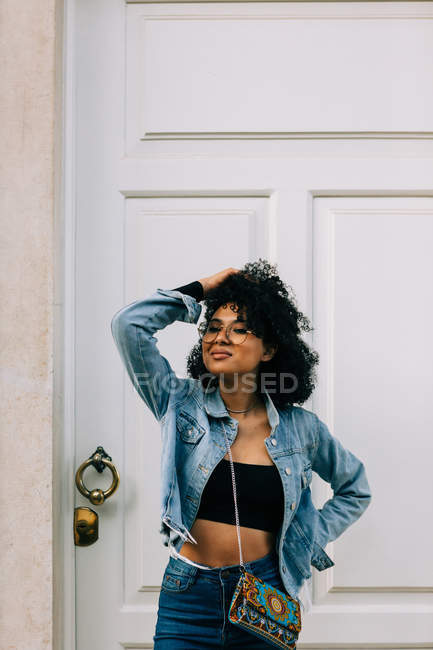 Trendy donna afroamericana in crop top nero e jeans in piedi dalla porta — Foto stock