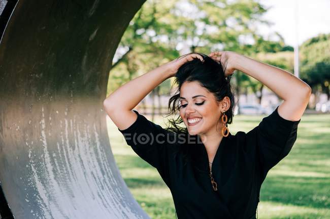 Vista laterale della donna seduta in una panchina creativa a forma di anello e sorridente a Lisbona durante l'estate — Foto stock