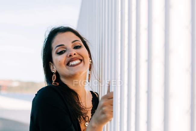 У сонячний день красива стильна жінка в чорному одязі стоїть біля мосту з міським ландшафтом у Лісабоні. — стокове фото