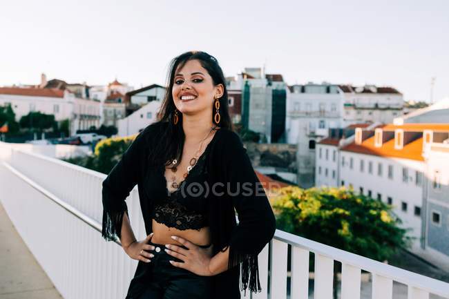 Bella donna elegante in abito nero in piedi vicino al ponte con paesaggio urbano a Lisbona nella giornata di sole — Foto stock