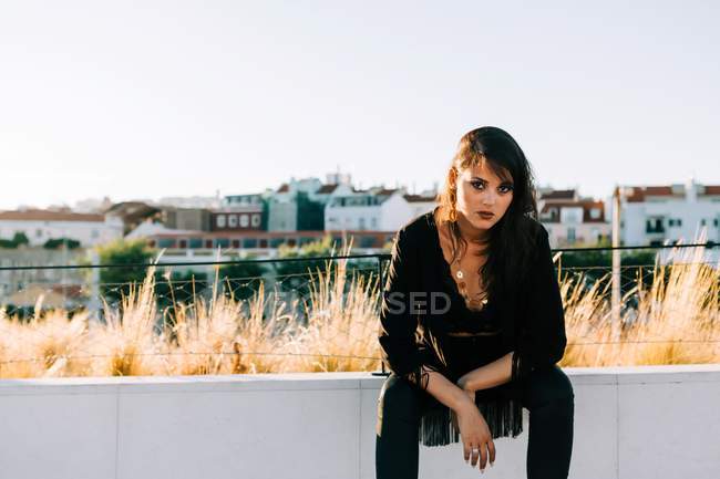Bella donna elegante in abito nero seduta con paesaggio urbano a Lisbona nella giornata di sole — Foto stock