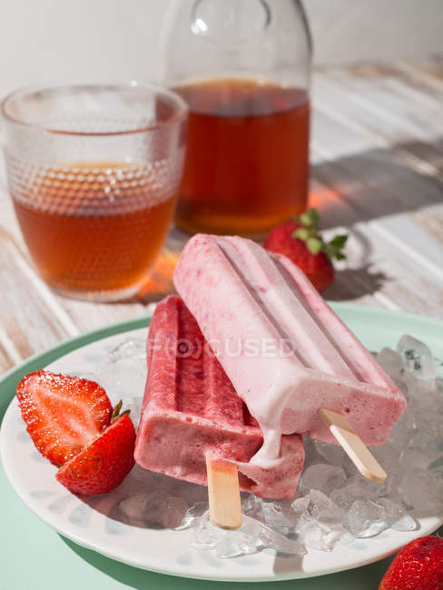 Sorvete de morango fresco em prato gelado perto de vidro de chá frio — Fotografia de Stock