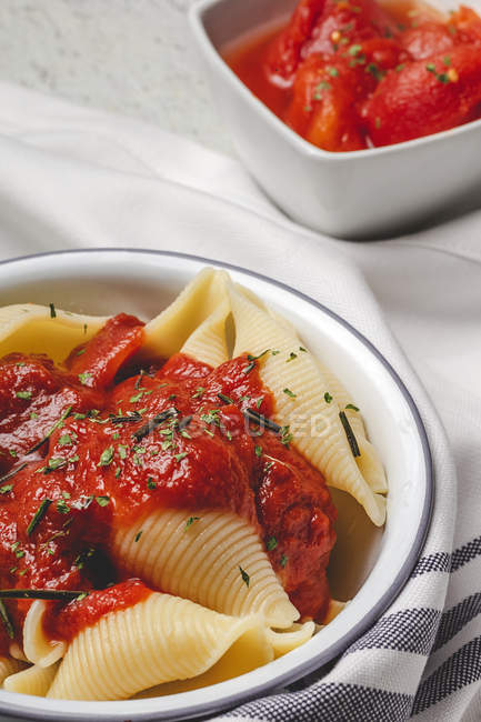 Смачна кончіглі паста, посипана базиліком та червоним томатним соусом, подається на білій тарілці — стокове фото