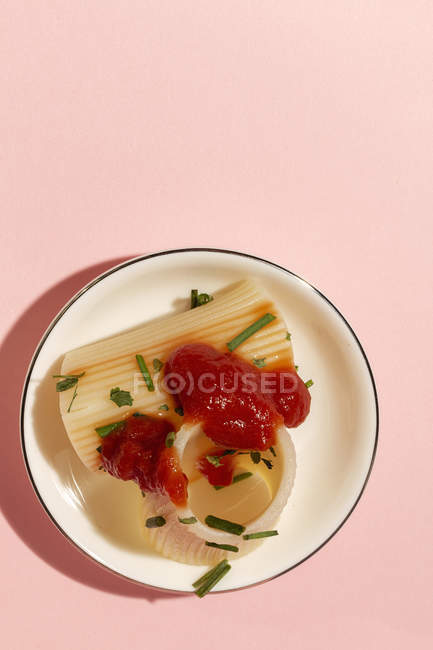 Cannelloni cotti con salsa di pomodoro ed erbe aromatiche serviti su piatto bianco su fondo rosa — Foto stock