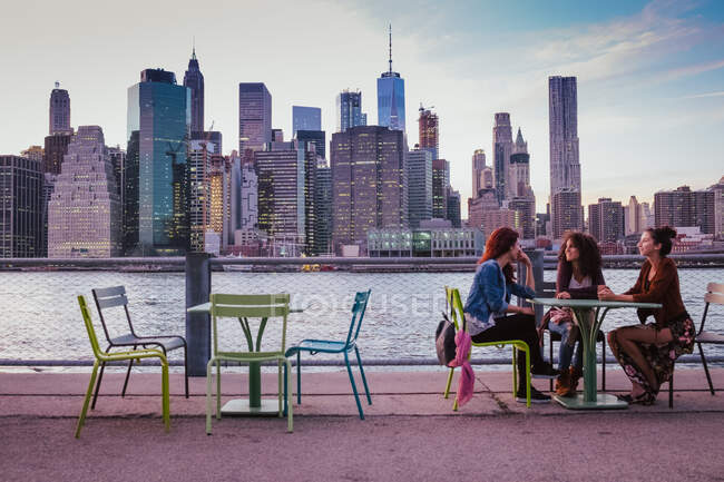Amici seduti sulla terrazza con sfondo New York la sera — Foto stock