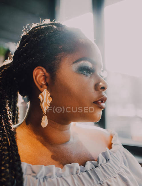 Portrait de vue latérale de belle jeune femme noire incurvée avec un maquillage lumineux en robe hors épaule — Photo de stock