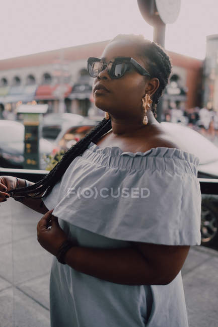 Attraente giovane donna nera con trucco luminoso in abito off-spalla in piedi sulla strada al tramonto — Foto stock