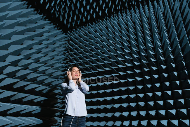 Mulher nova bonita que aprecia a música na sala de som moderna com paredes spiky — Fotografia de Stock