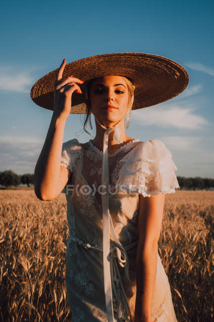 Mulher em chapéu redondo grande no meio do campo de trigo — Fotografia de Stock