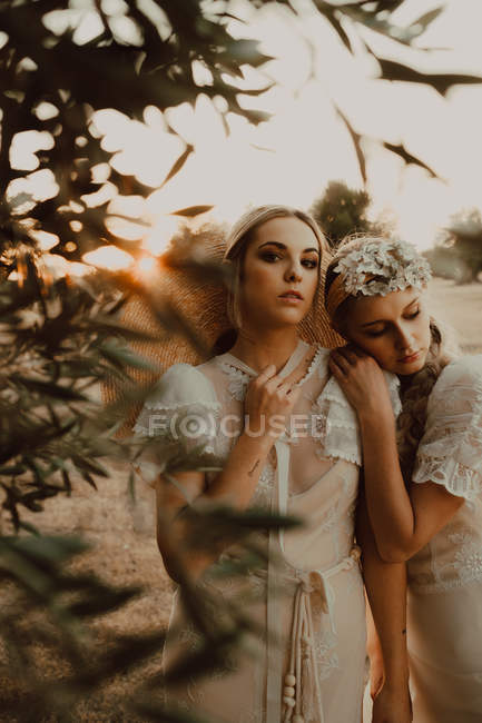Affascinanti spose sottili con fiori in giardino con ulivi — Foto stock