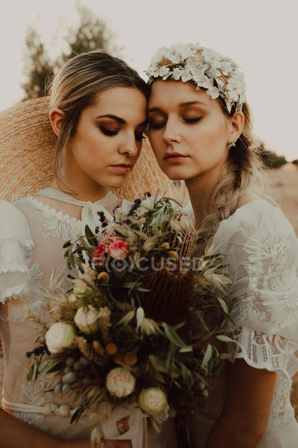 Чарівні наречені з квітами в саду з оливковими деревами — стокове фото