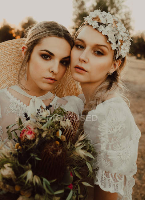 Encantadoras novias con flores en el jardín con olivos - foto de stock