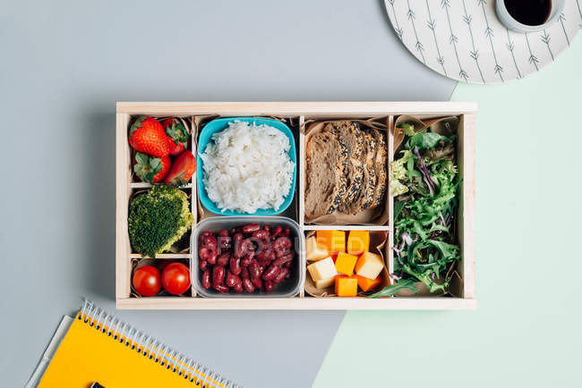 Food box with diet ingredients by copybook and plate — Stock Photo