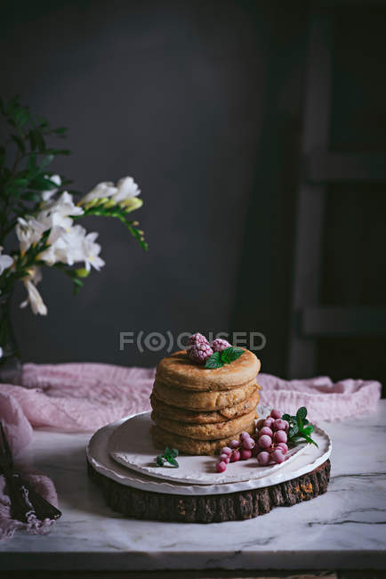 Pila de panqueques de frambuesa con bayas frescas en plato de porcelana sobre fondo oscuro - foto de stock