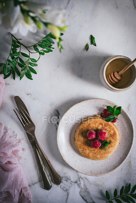 Leckere Pfannkuchen mit frischen Himbeeren und Minzblättern auf weißem Teller auf Marmor-Tischplatte — Stockfoto