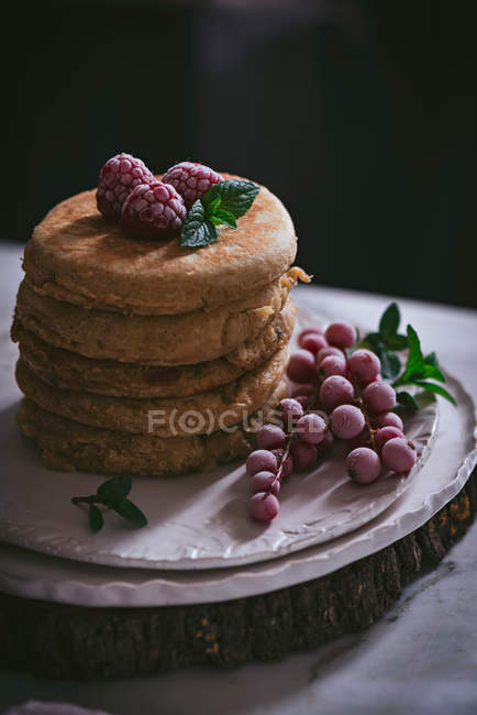 Stack of raspberry pancakes with fresh berries on porcelain plate over dark background — Stock Photo
