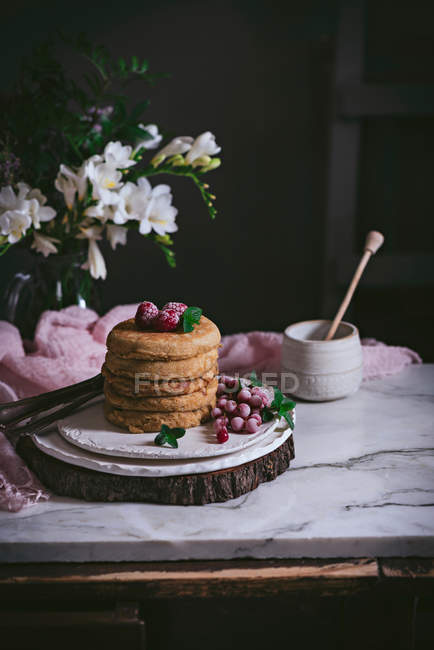 Стек малинових млинців зі свіжими ягодами на порцеляновій тарілці на темному фоні — стокове фото