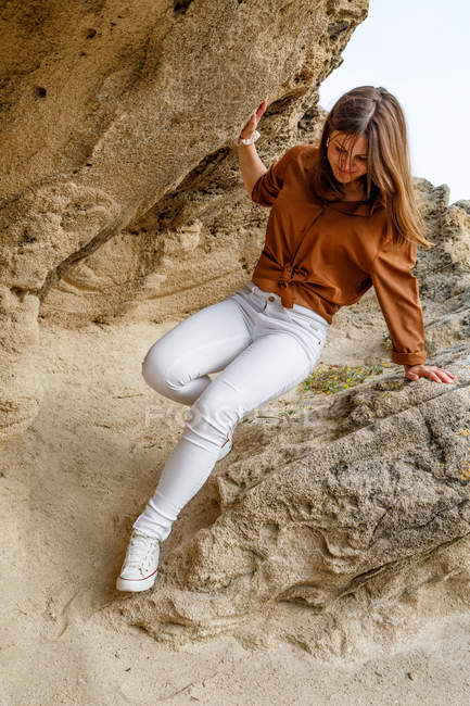 Hermosa mujer aventurera de vaqueros blancos caminando sobre piedras rocosas en el desierto. - foto de stock