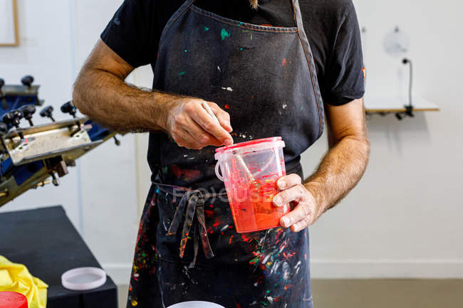 Homem de cultura concentrado usando avental sujo misturando várias tintas para serigrafia em oficina — Fotografia de Stock