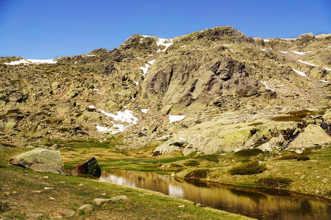 Kleiner See am Fuße des felsigen Berges mit Schnee in Sierra de Guadarrama Spanien — Stockfoto