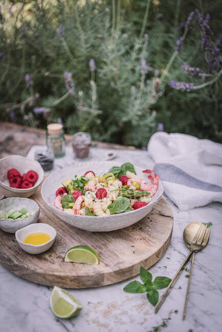 From above appetizing salad and sauce berries sliced lime on wooden stand with salt and pepper on table — Stock Photo