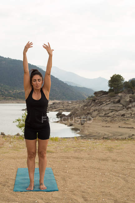 Жінка робить йогу на відкритому повітрі в похмурий день на березі дамби — стокове фото
