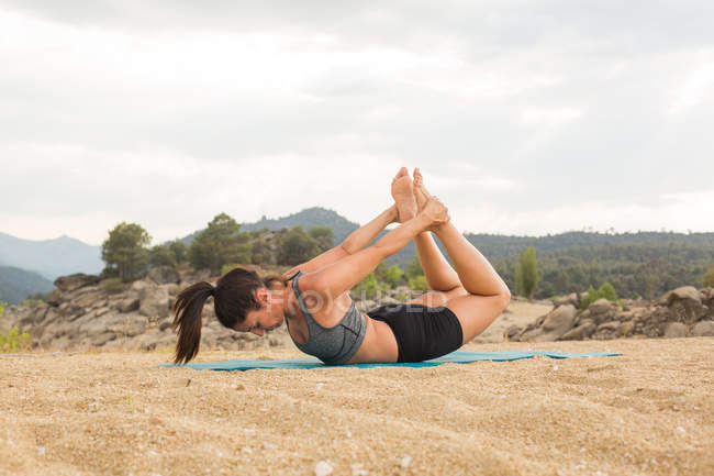 Mitte erwachsene Frau macht Yoga im Freien am Damm Strand — Stockfoto