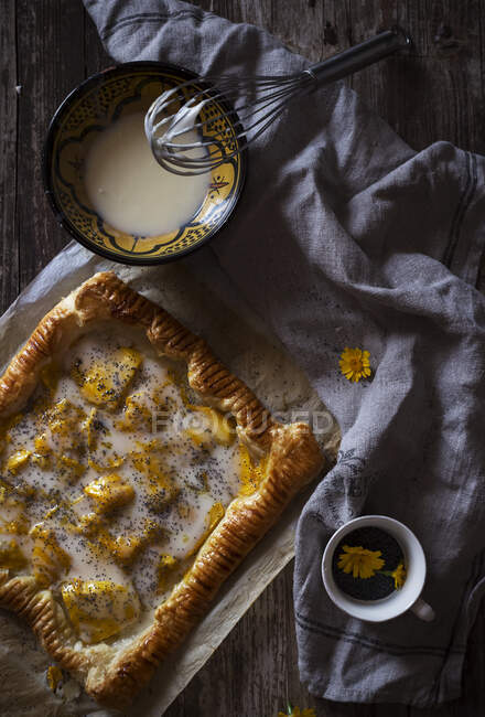 De dessus tasse de tisane fraîche et bol avec sauce crémeuse placé sur une serviette en tissu près de délicieuse tarte — Photo de stock