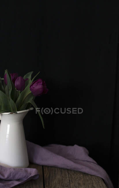 Tiny metal bucket with bright purple flowers placed on lumber tabletop — Stock Photo